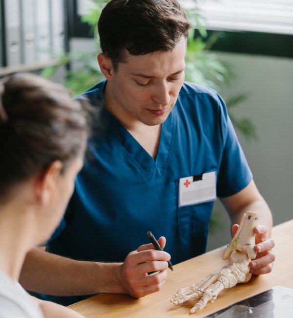 Physician demonstrating a foot model while discussing treatment options with a patient.